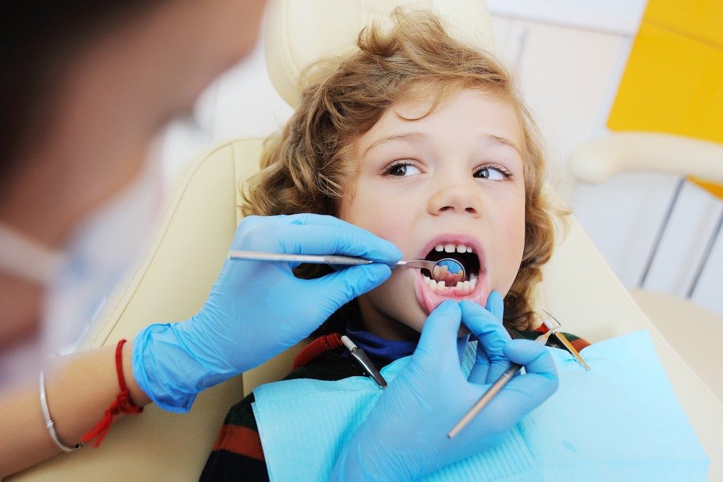 kid getting his tooth checked by dentist