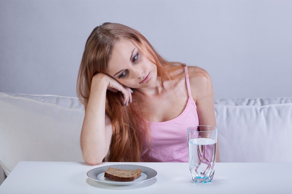 depressed girl starring at the bread on her plate