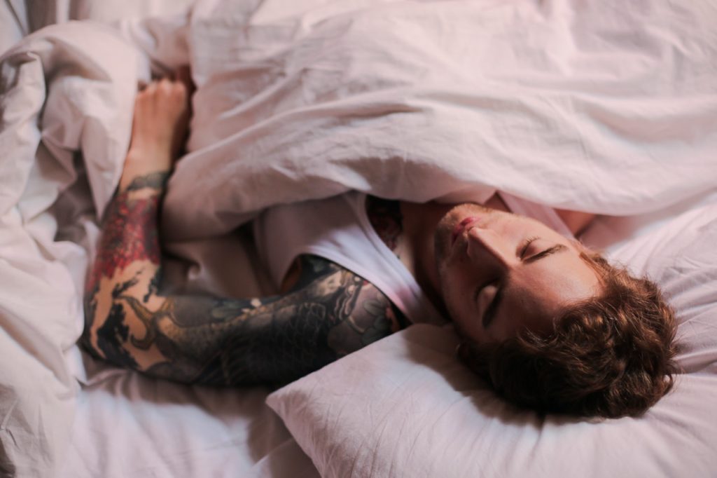 man with sleeve tattoo sleeping