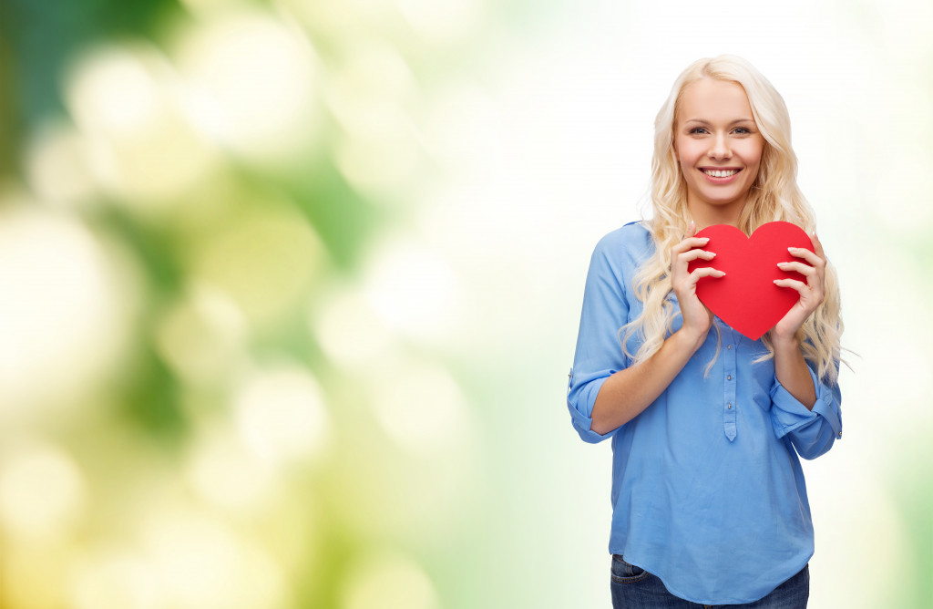adult woman smiling while holding a heart