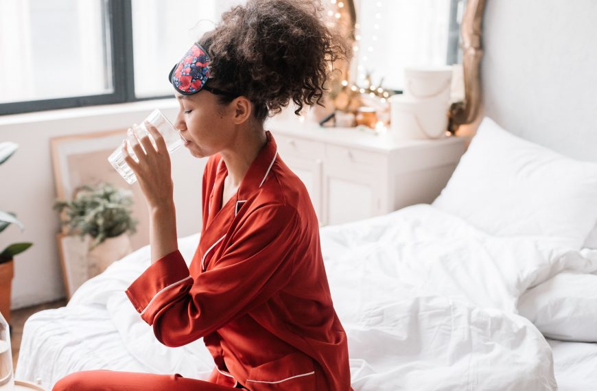 woman in pajamas, drinking water in bed